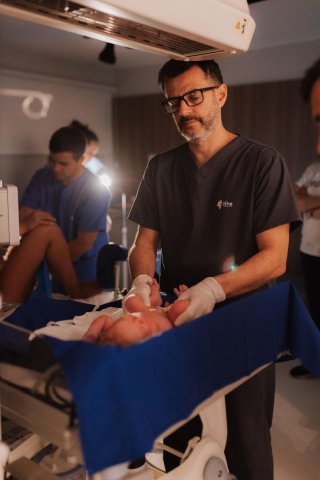 Медицинский работник помогает новорожденному в хорошо освещенной родильной палате, фокусируясь на моментах заботы